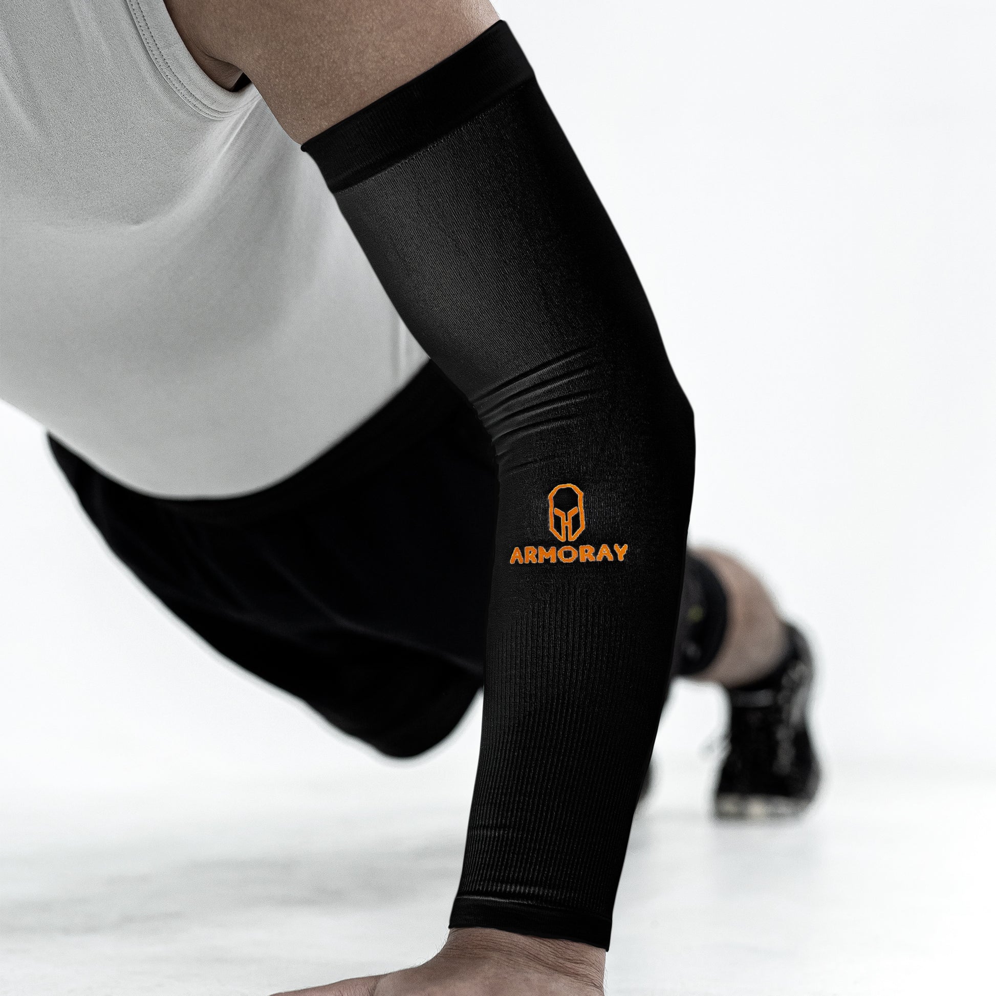 A person doing a push-up wears black Armoray® Arm Sleeves by ARMORAY Basics for sun protection, paired with a white shirt and black shorts.