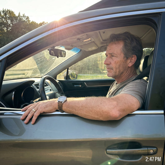 A driver's left arm resting on the door in bright afternoon sunlight with no arm protection visible.