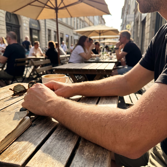 A person's arms visible while sitting at an outdoor cafe table on a bright sunny afternoon.