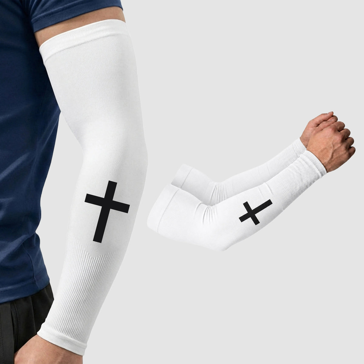 A person is wearing an ARMORAY Faith Series white compression arm sleeve featuring a bold black cross design; this scripture sleeve delivers UPF 50+ sun protection and moisture-wicking comfort. A second Faith Series sleeve, displaying the same design, is shown separately.