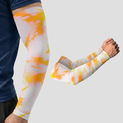 A person wears Armoray® Patterned Arm Sleeves by ARMORAY, shown here in a vibrant orange and yellow tie-dye design on a white base. These UPF 50+ sleeves deliver outstanding sun protection. A close-up view displays both sleeves separately against a light grey background.