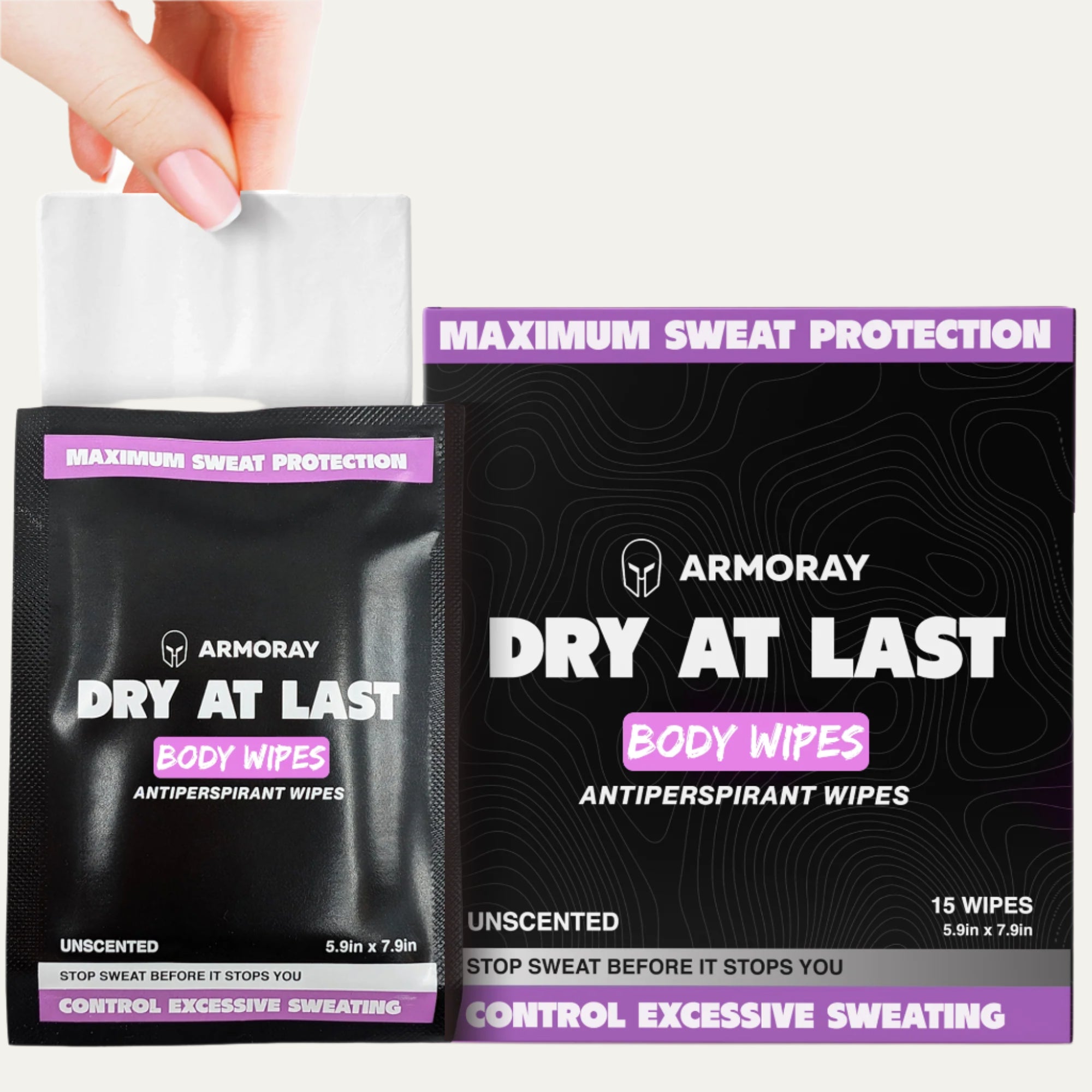 A hand pulls an Armoray® Dry At Last Antiperspirant Body Wipe from a black and purple ARMORAY Basics package labeled unscented, offering long-lasting protection, with the box beside it.