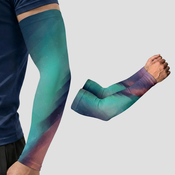 A person is wearing a dark blue shirt and ARMORAY Armoray® Patterned Arm Sleeves—featuring a colorful gradient design and UPF 50+ sun protection—while another pair of the same sleeves is folded beside them.
