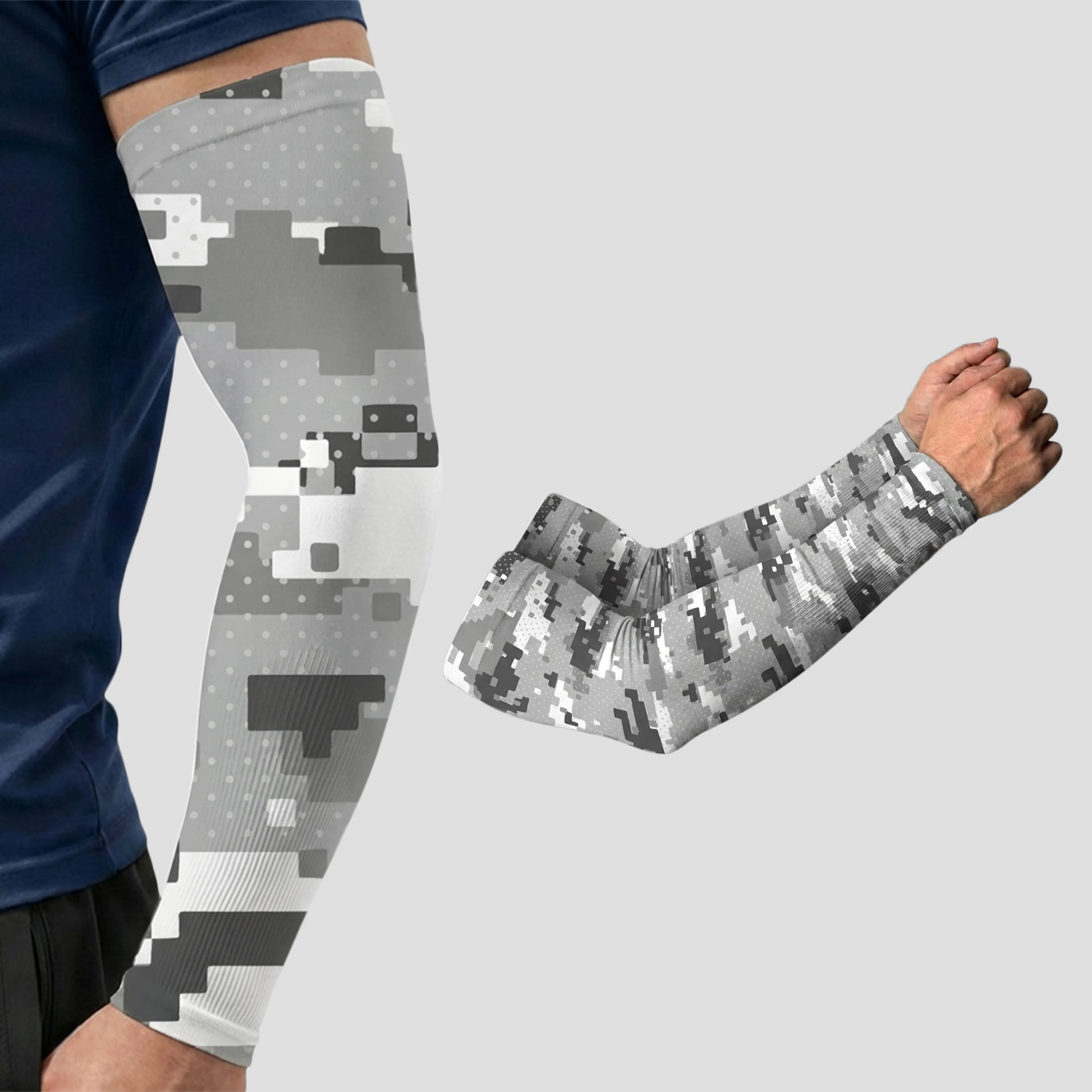 Two arms featuring Armoray® Patterned Arm Sleeves by ARMORAY are shown against a plain light background in a gray digital camouflage design; one arm is worn by a person, while the other sleeve is displayed separately, showcasing these designer sleeves that provide UPF 50+ sun protection and are available in 35+ bold looks.