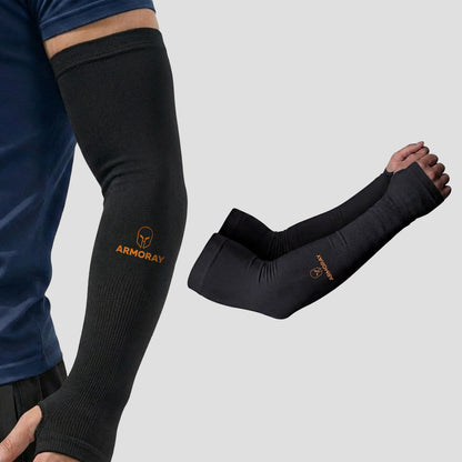 Wearing the Armoray® Thumbhole Arm Sleeves — Designed for Total Protection by ARMORAY, a person showcases the black compression sleeve with extended hand coverage and a comfortable thumbhole design for enhanced support. Beside them lies a matching pair of identical sleeves on a plain background, making these sleeves perfect for sun protection during outdoor activities.