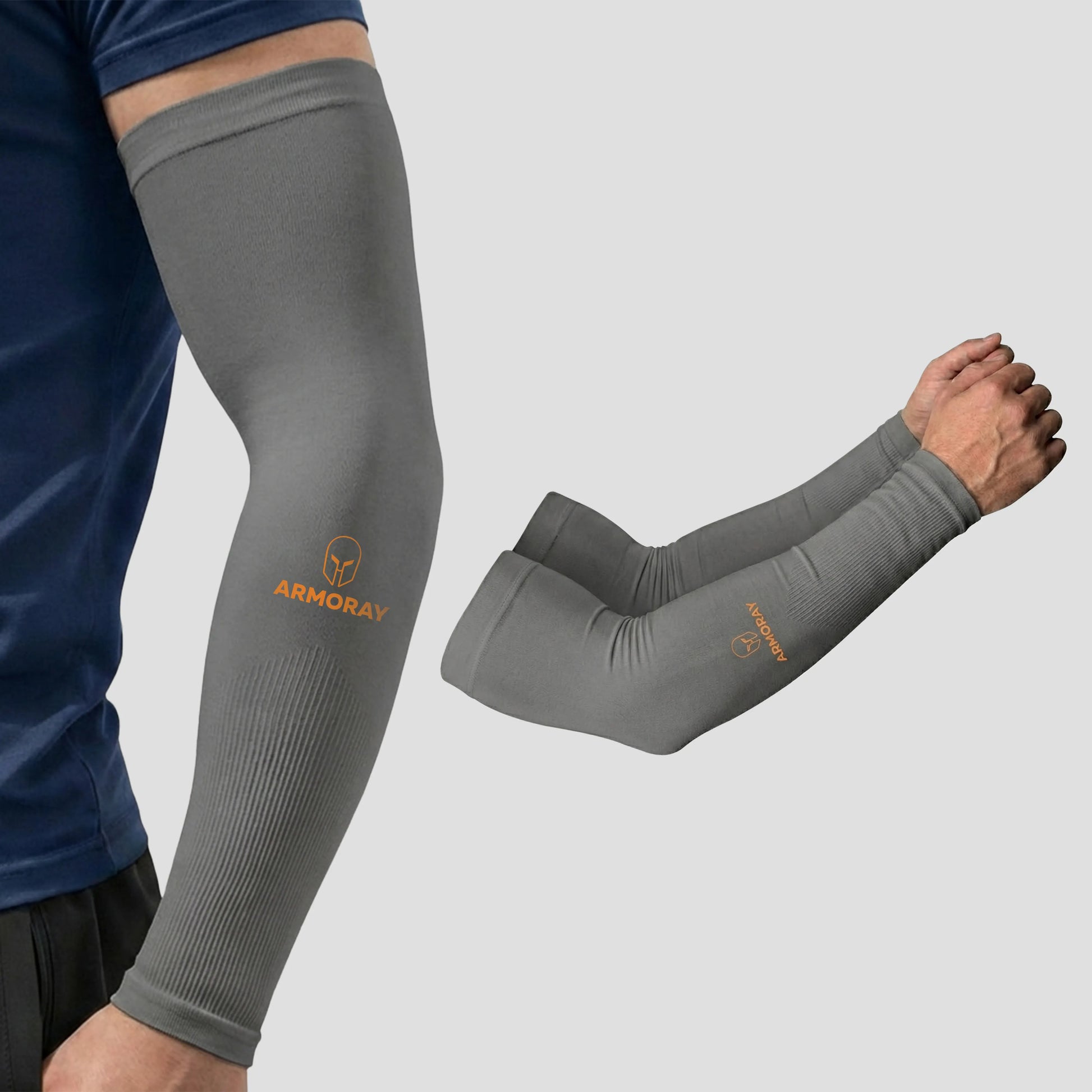 A person wears an Armoray® Classic Arm Sleeve in gray featuring the ARMORAY logo, while an additional pair of sleeves is displayed separately against a plain background.