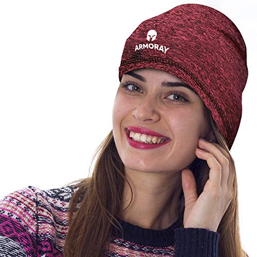A woman smiles wearing the Armoray Skull Cap by ARMORAY Basics—a red knit beanie with a helmet logo, designed as a cozy running hat that doubles as a sweat-wicking skull cap for men or women.