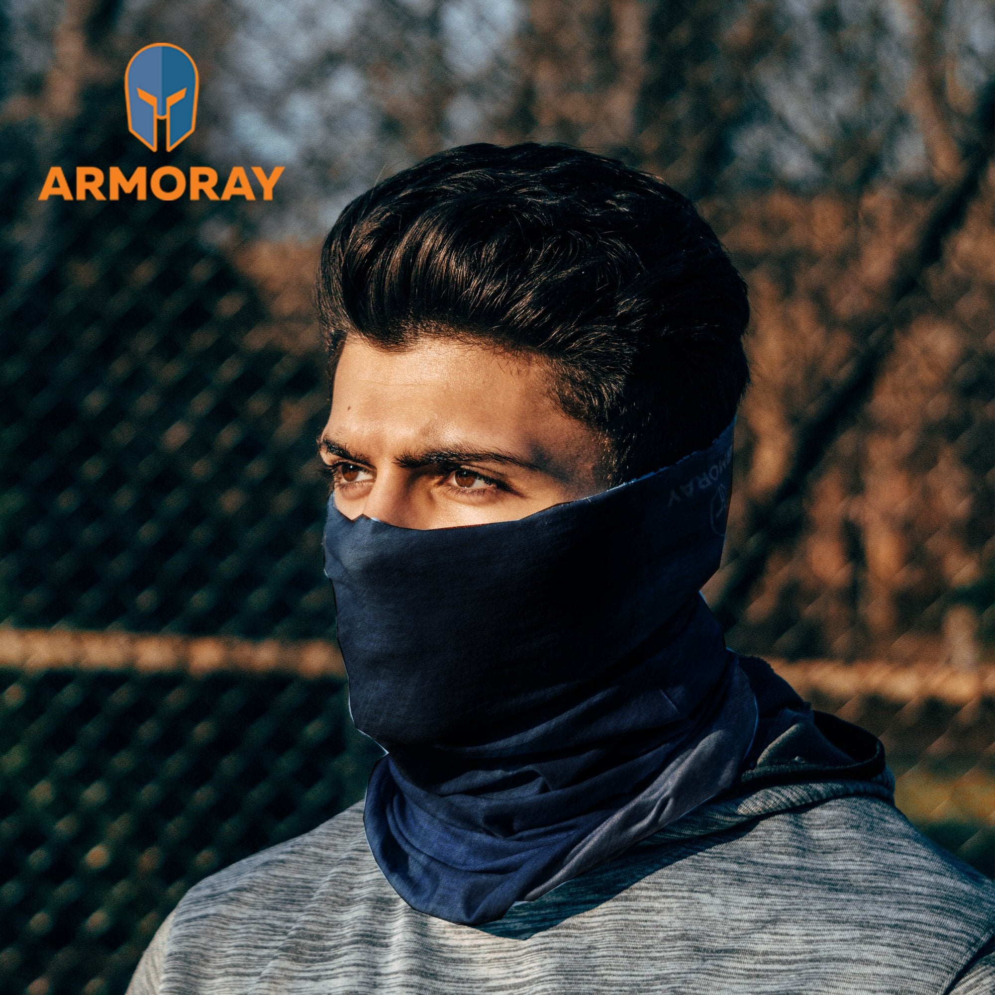 A man stands outdoors wearing an Armoray® Bandana—designed for the outdoors—in blue, covering his nose and mouth. The ARMORAY logo appears in the top left corner of the image, highlighting the bandana’s sweat-resistant performance and rugged quality.